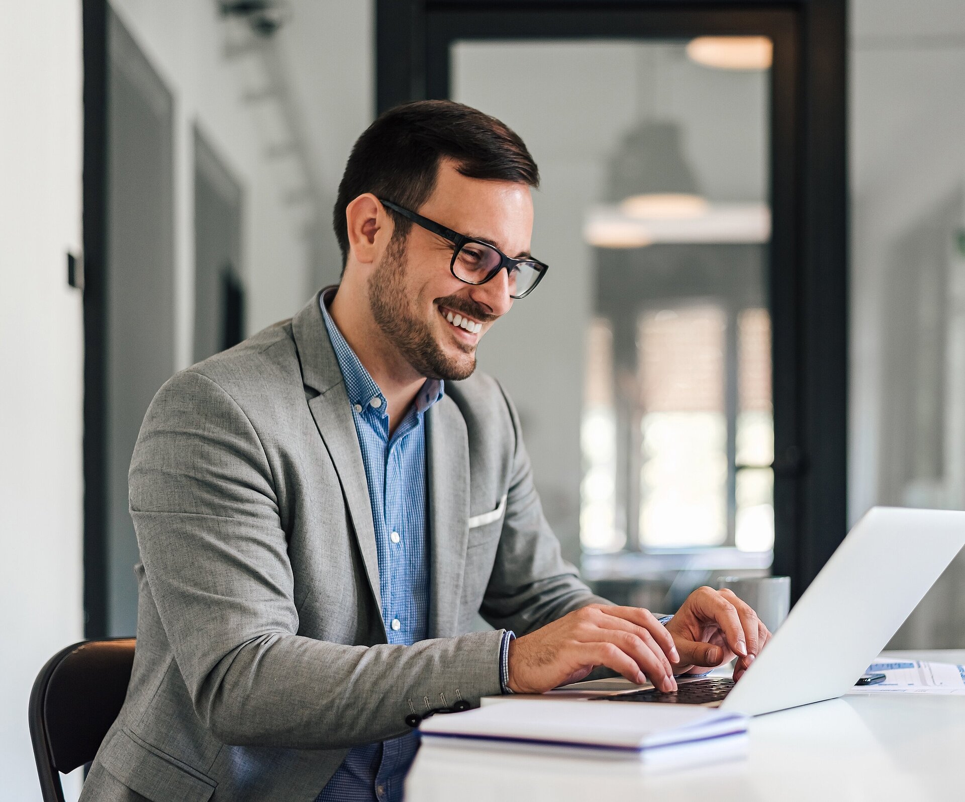 Mann arbeitet am Laptop im Büro und lacht