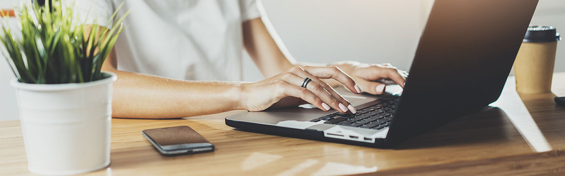 Frau sitzt an einem Schreibtisch und arbeitet auf einem Laptop