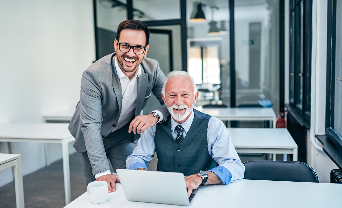 Zwei Männer arbeiten im Büro mit Laptop