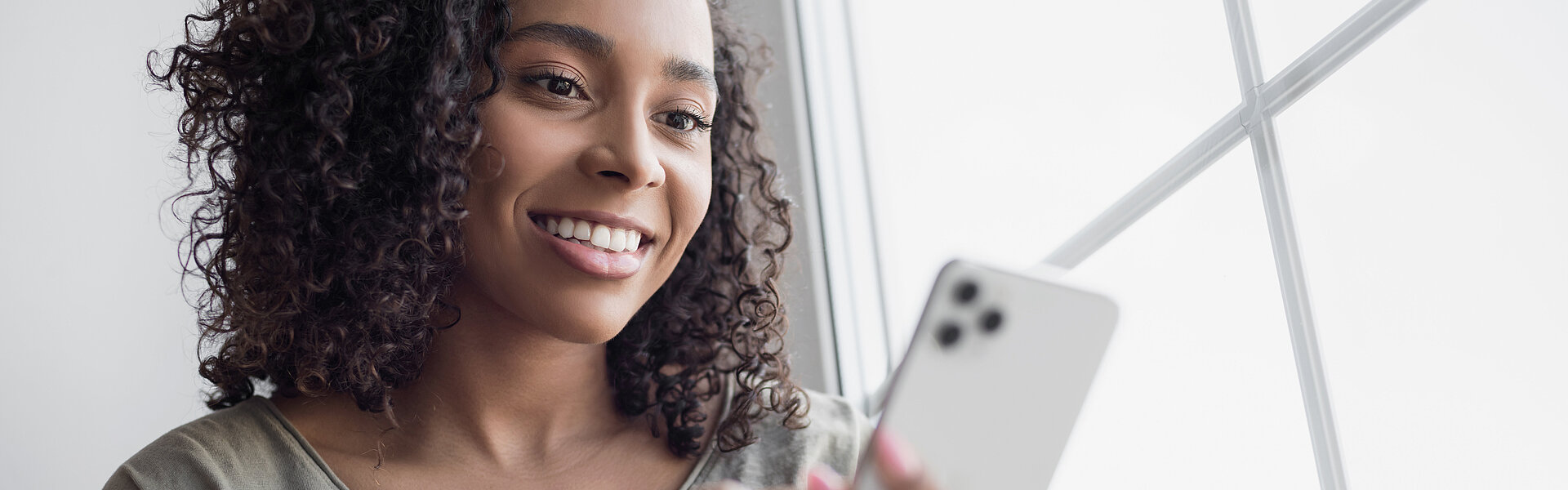 Frau lächelt während Sie ihr Smartphone bedient