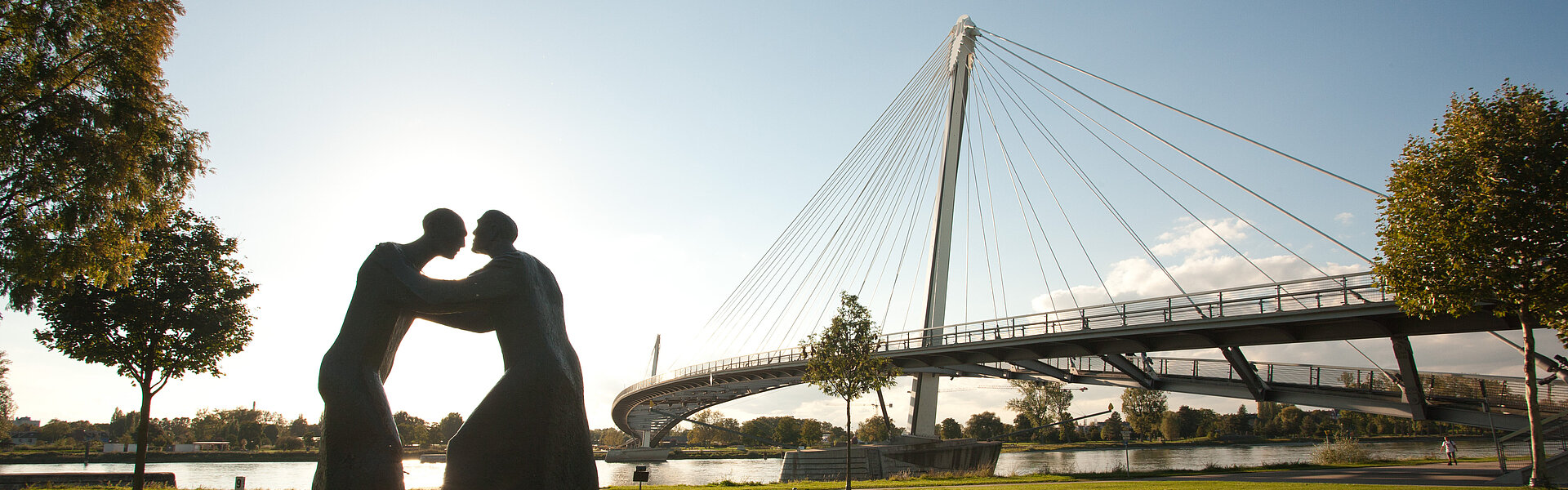 Statue auf grüner Wiese vor einer Brücke in Kehl