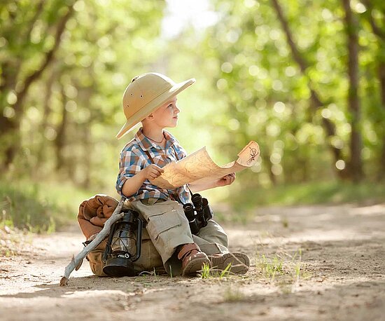 Wanderer kleiner Junge im Wald mit Karte 