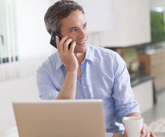 Mann im Homeoffice telefoniert an seinem Arbeitsplatz